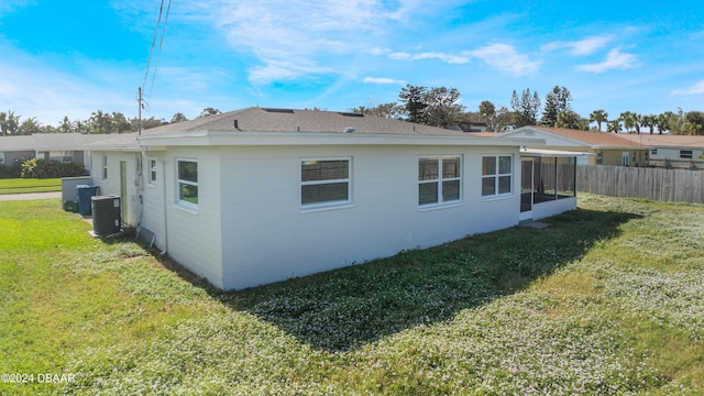 view of home's exterior with a yard, central AC, and a sunroom