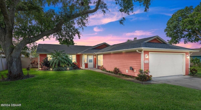 ranch-style home with a garage and a lawn