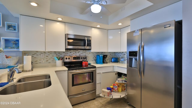 kitchen with stainless steel appliances, sink, light tile patterned floors, white cabinets, and decorative backsplash