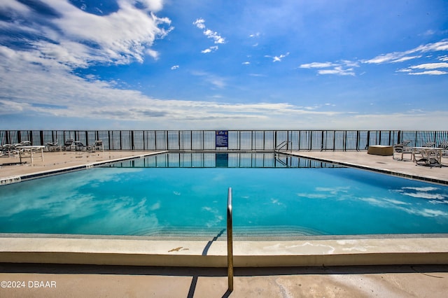 view of swimming pool featuring a water view and a patio