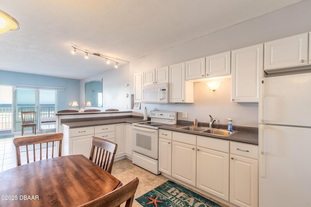 kitchen with kitchen peninsula, white appliances, sink, white cabinetry, and light tile patterned flooring