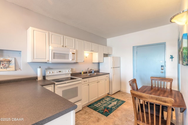 kitchen with white cabinetry, sink, light tile patterned floors, and white appliances