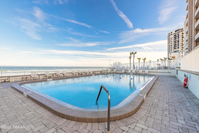 view of swimming pool featuring a water view and a patio area