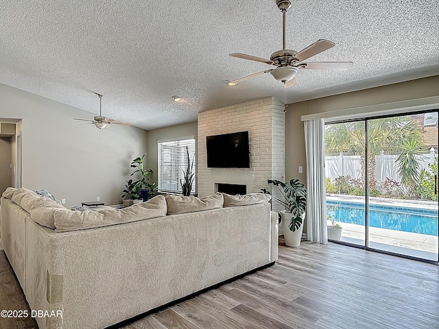 7 Heather Ln, Ormond Beach, FL 32174 - living area with a ceiling fan, a textured ceiling, light wood finished floors, and a brick fireplace