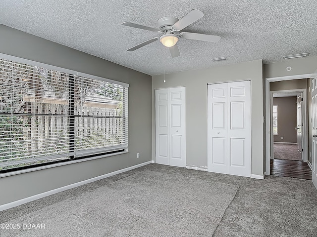 7 Heather Ln, Ormond Beach, FL 32174 - unfurnished bedroom with two closets, carpet, a textured ceiling, baseboards, and a ceiling fan