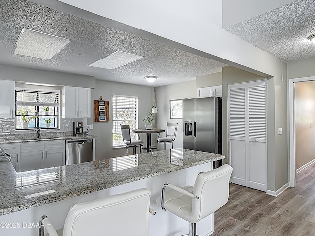 7 Heather Ln, Ormond Beach, FL 32174 - kitchen featuring appliances with stainless steel finishes, a textured ceiling, dark wood finished floors, stone counters, and a sink