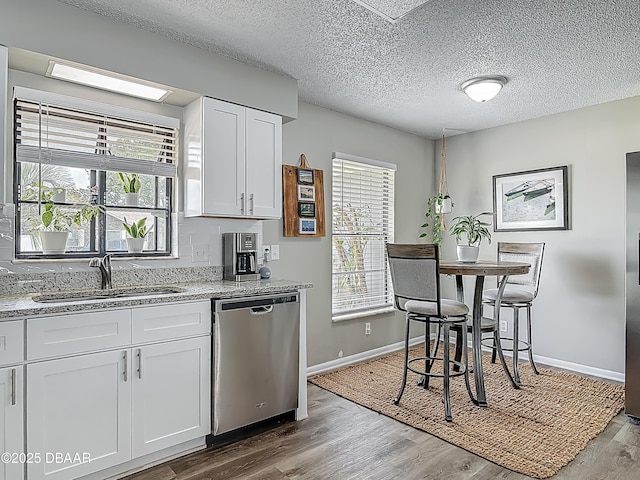 7 Heather Ln, Ormond Beach, FL 32174 - kitchen featuring stainless steel dishwasher, a sink, baseboards, light wood-style floors, and white cabinetry