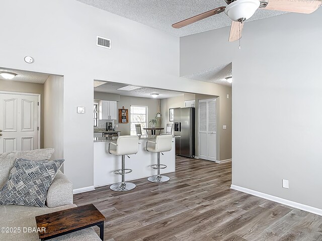 7 Heather Ln, Ormond Beach, FL 32174 - kitchen with stainless steel fridge, a peninsula, a breakfast bar area, dark wood-type flooring, and ceiling fan