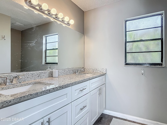 7 Heather Ln, Ormond Beach, FL 32174 - full bathroom featuring a textured ceiling, double vanity, baseboards, and wood finished floors