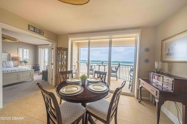 dining area featuring a water view, light tile patterned floors, a healthy amount of sunlight, and a textured ceiling