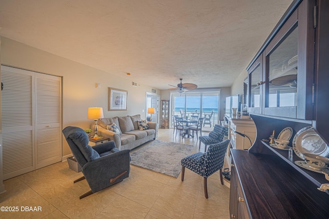 living room featuring ceiling fan, a textured ceiling, and light tile patterned flooring