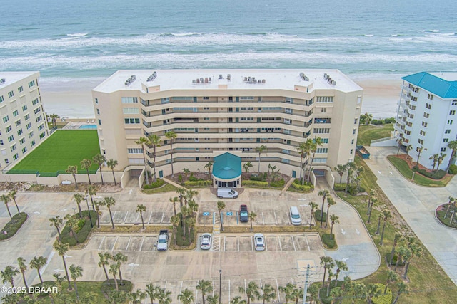 view of building exterior featuring a water view and a beach view