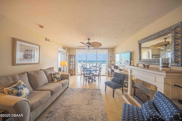 living room featuring a textured ceiling, ceiling fan, and light tile patterned floors