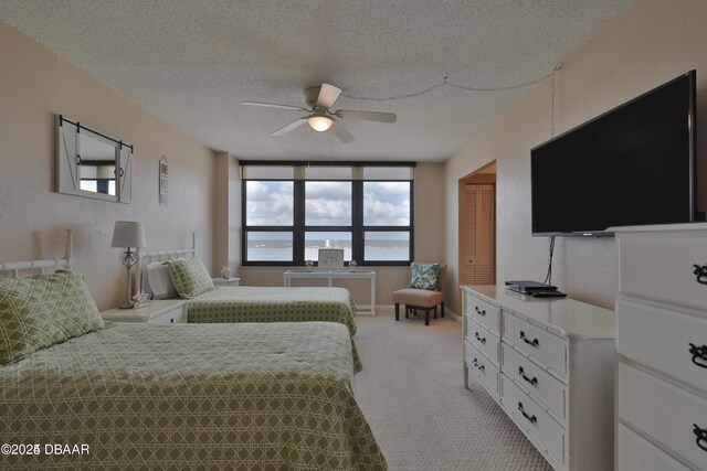 3051 S Atlantic Ave Unit 1806, Daytona Beach Shores, FL 32118 - bedroom featuring a textured ceiling, multiple windows, light colored carpet, a closet, and ceiling fan