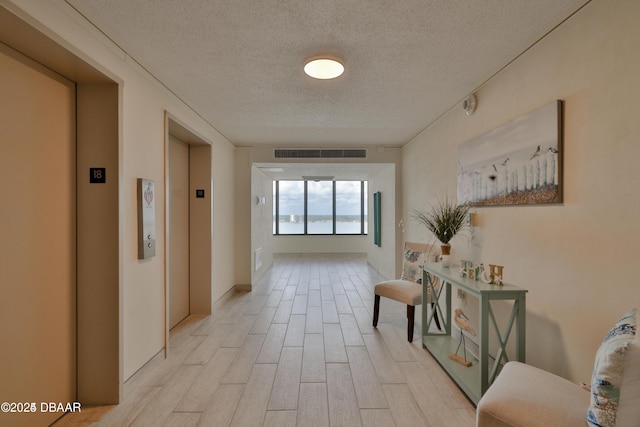 3051 S Atlantic Ave Unit 1806, Daytona Beach Shores, FL 32118 - hallway with elevator, a textured ceiling, and light wood-style flooring