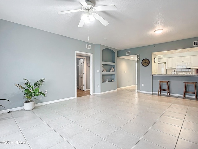 5300 S Atlantic Ave Unit 9-403, New Smyrna Beach, FL 32169 - unfurnished living room with built in features, baseboards, light tile patterned floors, ceiling fan, and a textured ceiling
