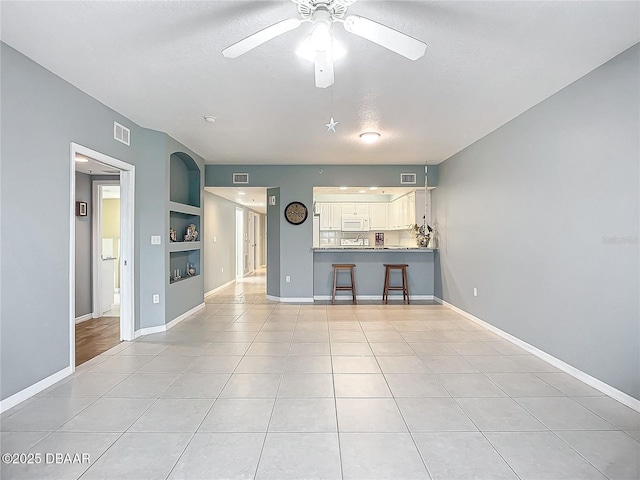 5300 S Atlantic Ave Unit 9-403, New Smyrna Beach, FL 32169 - unfurnished living room featuring baseboards, a textured ceiling, visible vents, ceiling fan, and built in shelves