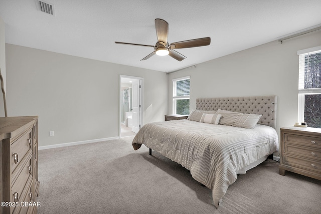 bedroom with ceiling fan, light colored carpet, and ensuite bathroom