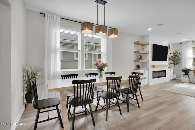 dining room featuring a large fireplace and light hardwood / wood-style flooring