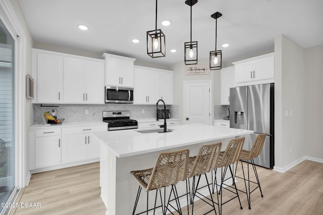 kitchen with sink, white cabinetry, appliances with stainless steel finishes, and a kitchen island with sink