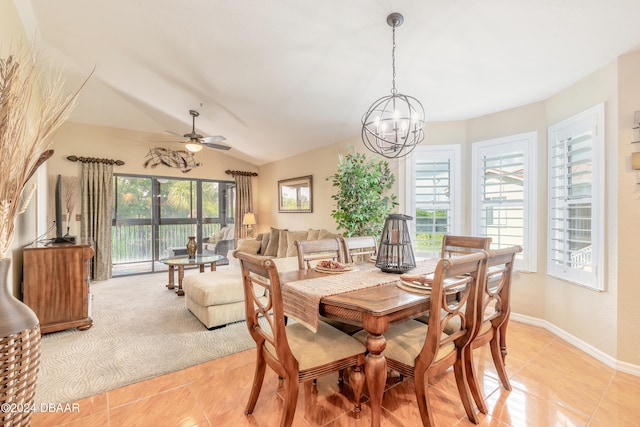 tiled dining space with ceiling fan with notable chandelier and lofted ceiling