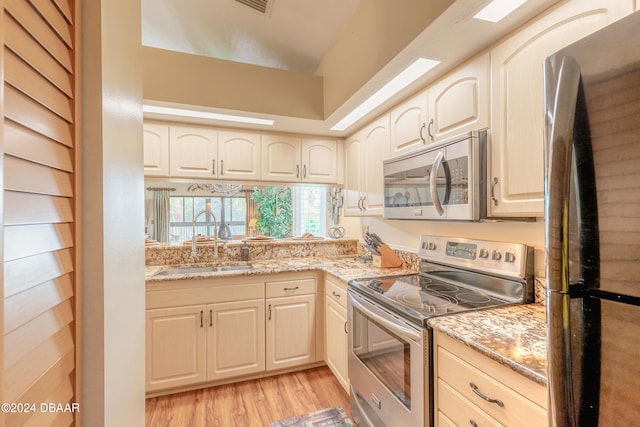 kitchen featuring light stone countertops, sink, light hardwood / wood-style flooring, and appliances with stainless steel finishes