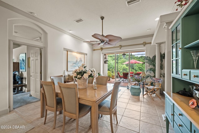 tiled dining space with ornate columns, a textured ceiling, ceiling fan, and crown molding