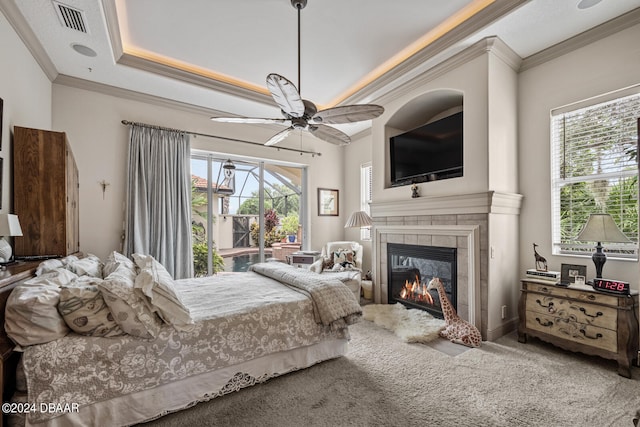 bedroom with multiple windows, carpet flooring, a tile fireplace, and ceiling fan