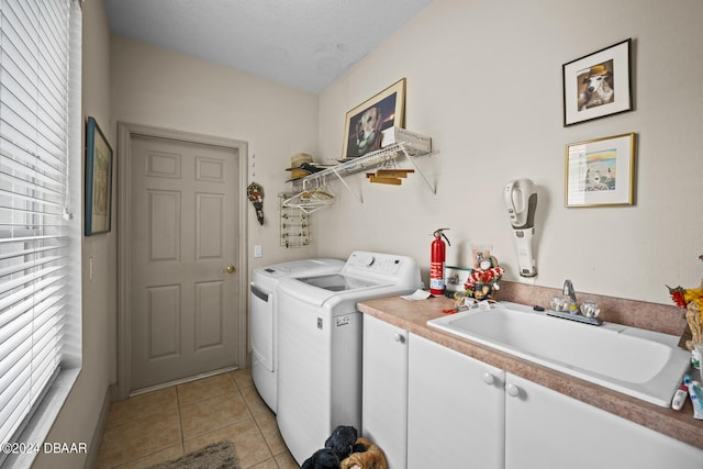 laundry room with cabinets, a textured ceiling, sink, light tile patterned floors, and washing machine and dryer