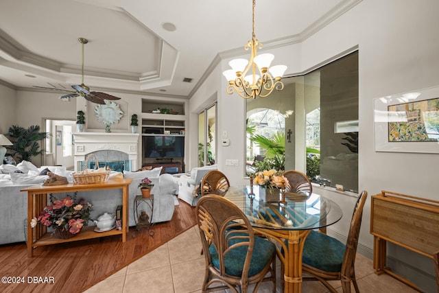 dining space featuring ceiling fan with notable chandelier, light wood-type flooring, crown molding, and a tray ceiling