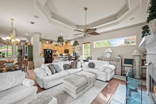 living room with wood-type flooring, crown molding, and a tray ceiling