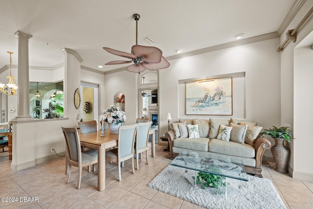 tiled dining area featuring a fireplace, ceiling fan, crown molding, and decorative columns