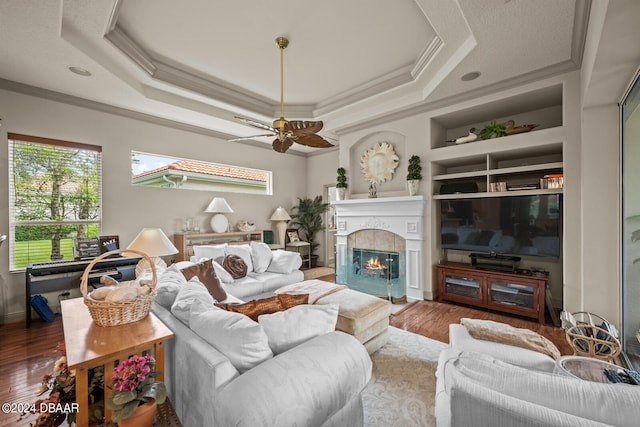 living room with a fireplace, wood-type flooring, crown molding, and built in shelves