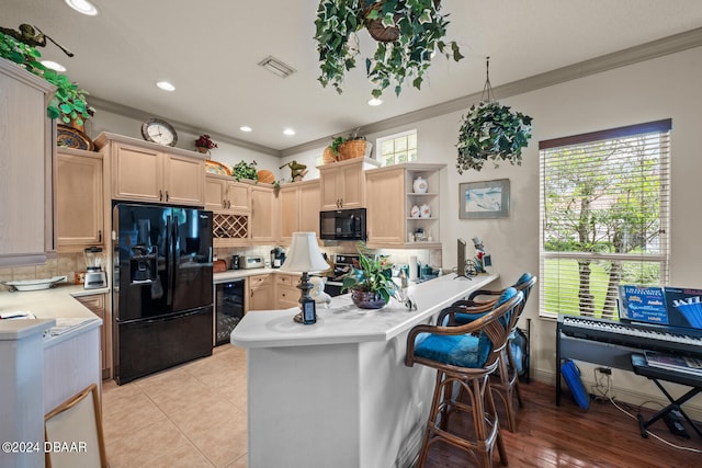 kitchen with black appliances, light brown cabinetry, decorative backsplash, beverage cooler, and kitchen peninsula