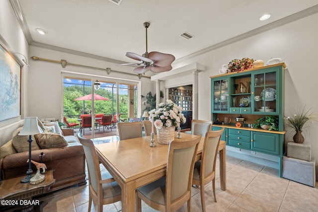 tiled dining space featuring ornamental molding, ceiling fan, and ornate columns