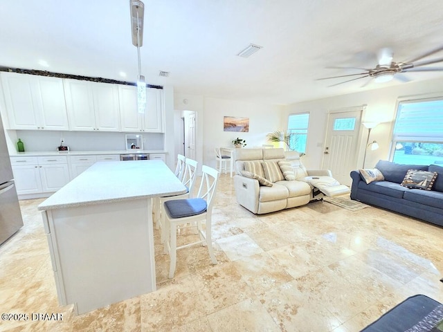 421 University Blvd, Daytona Beach, FL 32118 - kitchen with open floor plan, ceiling fan, light countertops, white cabinets, and a kitchen island