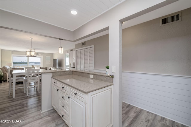 3606 S Peninsula Dr Unit 406, Port Orange, FL 32127 - kitchen featuring open floor plan, light wood finished floors, light stone counters, and white cabinetry