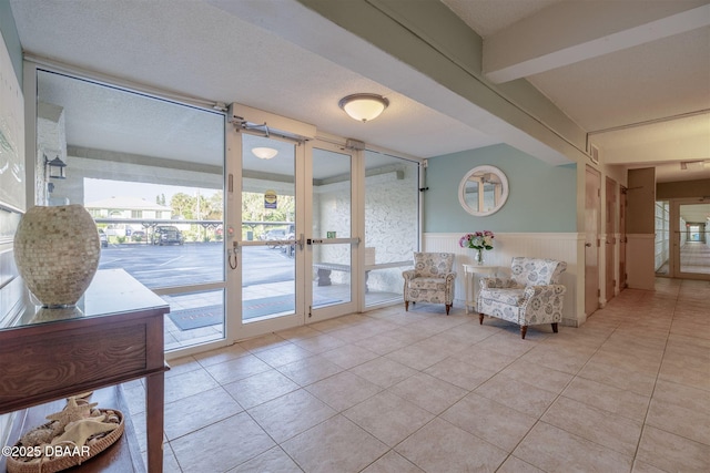 3606 S Peninsula Dr Unit 406, Port Orange, FL 32127 - sitting room featuring wainscoting, tile patterned flooring, french doors, and beamed ceiling
