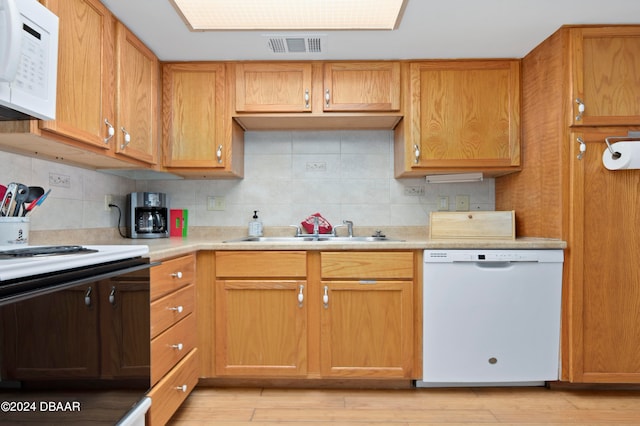 kitchen with white appliances, sink, light hardwood / wood-style flooring, and decorative backsplash