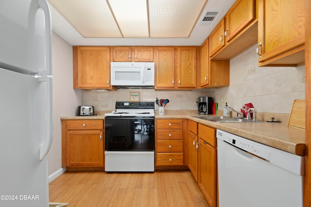 kitchen with white appliances, sink, light hardwood / wood-style flooring, and decorative backsplash