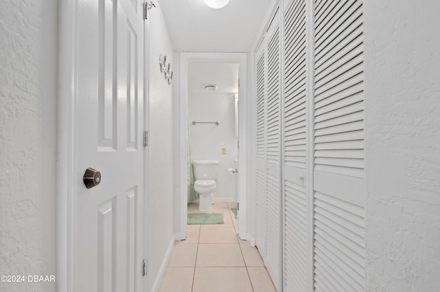 hall with a textured ceiling and light tile patterned floors