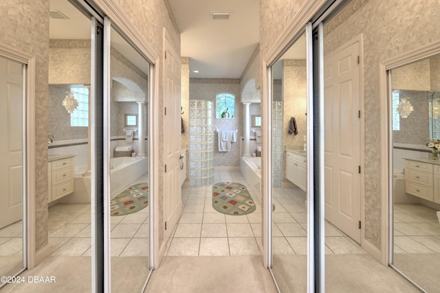 bathroom with a bathtub, vanity, and tile patterned flooring