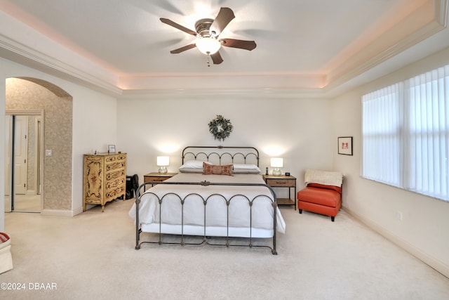 bedroom featuring ornamental molding, light carpet, ceiling fan, and a raised ceiling