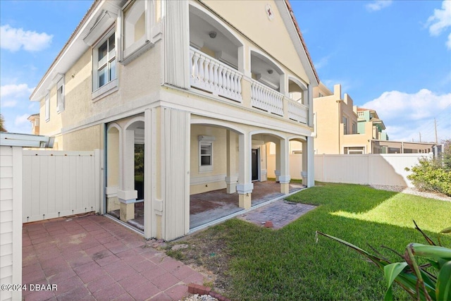 back of property with a patio, a balcony, and a yard