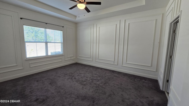 carpeted spare room featuring a raised ceiling and ceiling fan