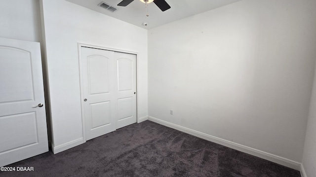 unfurnished bedroom featuring dark colored carpet, ceiling fan, and a closet