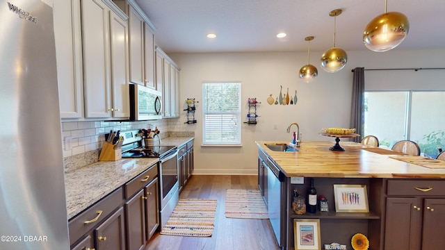 kitchen with wood counters, hanging light fixtures, sink, and appliances with stainless steel finishes