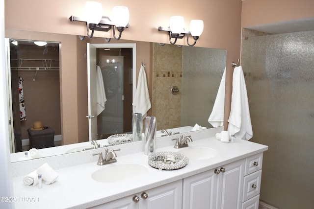 bathroom featuring a chandelier, double vanity, a tile shower, and a walk in closet