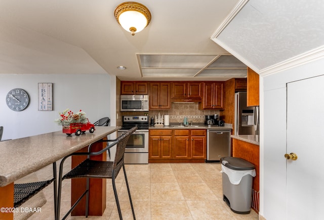 kitchen featuring tasteful backsplash, sink, a kitchen bar, light tile patterned floors, and stainless steel appliances