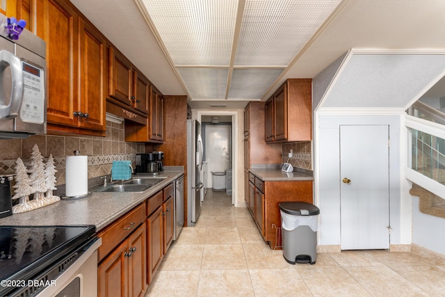 kitchen featuring light tile patterned flooring, appliances with stainless steel finishes, sink, and decorative backsplash